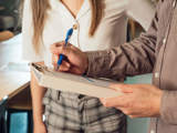 Man schrijft met een pen op een clipboard.